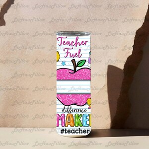 May include: A tall, stainless steel tumbler with a white background and the words "Teacher Fuel" in pink script. A pink apple graphic is in the center. The words "difference MAKE" are below the apple in colorful letters, with the hashtag #teacher.