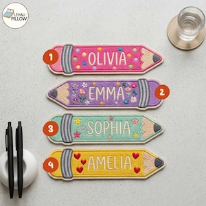 Può includere: Quattro toppe ricamate a forma di matita con nomi in bianco. La prima è rosa con pois colorati, la seconda viola con ricami floreali, la terza verde chiaro con motivi a stella e la quarta gialla con icone di cuori rossi.