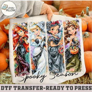 May include: A white fabric transfer featuring four cartoon princesses in Halloween-themed outfits, including witch hats and pumpkin accessories. The text "Spooky Season" is printed in a black cursive font at the bottom of the four vertical panels.