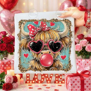 Peut inclure: Impression sur toile carr&eacute;e d'une vache des Highlands avec des lunettes en forme de c&oelig;ur et une bulle de chewing-gum. La vache a un n&oelig;ud rouge et est entour&eacute;e de c&oelig;urs et d'une bordure l&eacute;opard. Le mot "LOVE" est &eacute;crit en lettres lumineuses.