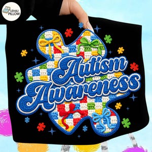 May include: Black pillowcase featuring a large puzzle piece design with the words "Autism Awareness" in blue script. The puzzle piece is checkered with various colors and adorned with colorful bows and puzzle piece accents.