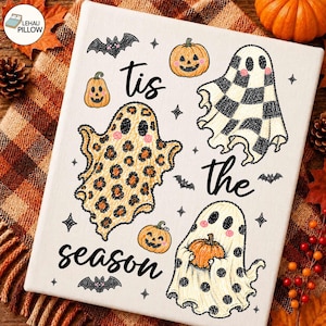 May include: A white rectangular canvas featuring the black text 'tis the season' surrounded by three ghosts and three pumpkins. One ghost has a leopard print pattern, one has a black and white checkerboard pattern, and one has black polka dots.