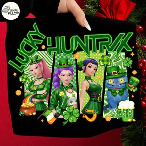 May include: Black t-shirt with a St. Patrick's Day design. The graphic features the text "LUCKY HUNT" in green, along with four cartoon characters in green outfits and hats, and a blue cat wearing a green hat. Additional elements include shamrocks, a pot of gold, and a horseshoe.