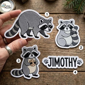 Op de afbeelding: Drie geborduurde wasbeerpatches en één naam-patch met de tekst JIMOTHY en pootafdrukken. De eerste patch toont een lopende wasbeer, de tweede een zittende wasbeer die zijn staart vasthoudt, en de derde een wasbeer met een koekje.