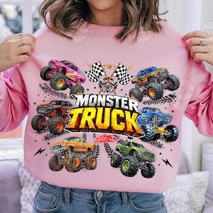 Może przedstawiać: R&oacute;żowa bluza z nadrukiem przedstawiającym sześć monster truck&oacute;w w r&oacute;żnych kolorach. Projekt zawiera napis "MONSTER TRUCK" w ż&oacute;łto-pomarańczowym kolorze, z szachownicami i gwiazdami.