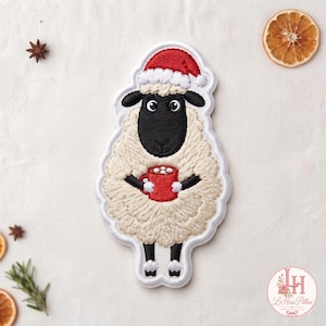 May include: An embroidered patch featuring a sheep with cream-colored wool, a black face, and black hooves. The sheep wears a red Santa hat with a white trim and holds a red mug filled with white marshmallows in its front hooves.