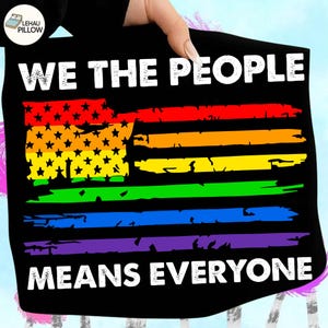 Könnte beinhalten: Ein schwarzes Stoffquadrat mit dem weißen Text WE THE PEOPLE oben und MEANS EVERYONE unten. In der Mitte befindet sich eine Grafik einer Flagge mit einem regenbogenfarbenen Streifenmuster und schwarzen Sternen auf gelbem Grund.