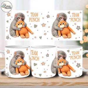 May include: White ceramic mug featuring a gray monkey hugging an orange stuffed monkey. The mug has the text "TEAM PUNCH" and decorative stars and hearts. A fun and playful design for a coffee or tea mug.