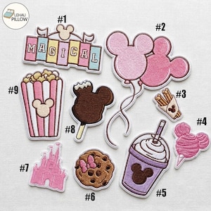 Könnte beinhalten: Eine Sammlung von neun gestickten Aufnähern mit Themenpark-Motiven, darunter ein Schild mit der Aufschrift MAGICAL, mausförmige Luftballons, Churros, Popcorn, eine Schokoleckerei, ein Keks mit Schleife, ein Schloss, ein Getränk und Zuckerwatte.
