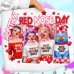 Op de afbeelding: Wit kussen met een ontwerp voor Red Nose Day. Het ontwerp toont drie cartoonvrouwen en een blauwe kat, allemaal met rode clownsneuzen. De tekst "RED NOSE DAY" is prominent aanwezig.