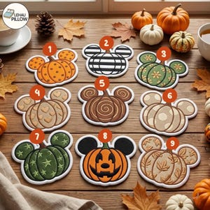 May include: Nine embroidered pumpkin-shaped coasters with mouse-ear silhouettes, numbered one through nine. Designs include polka dots, stripes, floral patterns, hearts, swirls, stars, a jack-o'-lantern face, and autumn leaves in orange, green, and brown.