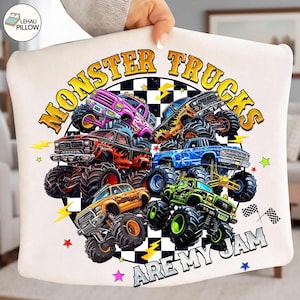 Peut inclure: Coussin blanc avec un motif color&eacute; de monster trucks. Le design pr&eacute;sente plusieurs monster trucks de diff&eacute;rentes couleurs, avec le texte "MONSTER TRUCKS ARE MY JAM" en gras. Des &eacute;toiles, des &eacute;clairs et des drapeaux &agrave; damier compl&egrave;tent le design.