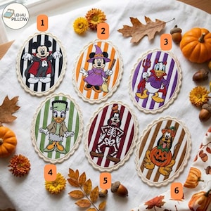 May include: Six oval embroidered patches featuring Disney characters in Halloween costumes: Mickey as a vampire, Minnie as a witch, Donald as a devil, Daisy as Frankenstein's monster, Goofy as a skeleton, and Pluto inside a pumpkin.