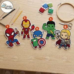 May include: Five embroidered patches featuring cartoon-style superhero characters labeled one through five. The characters include Spider-Man with a pencil, Iron Man with an apple, Captain America with a notebook and shield, Hulk with a ruler, and Thor with a hammer.