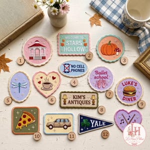May include: A collection of twelve embroidered patches featuring various designs including a gazebo, a pumpkin, a dragonfly, a coffee cup, ballet slippers, a burger, a pizza slice, a car, a Yale pennant, and signs reading Stars Hollow, No Cell Phones, and Kim's Antiques.