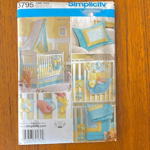 May include: Simplicity sewing pattern 3795 for nursery bedding and decor. The package features illustrations of a crib with a canopy, a pillow, a hanging organizer, and a quilt, all in a yellow, white, and light blue color scheme with flower accents.