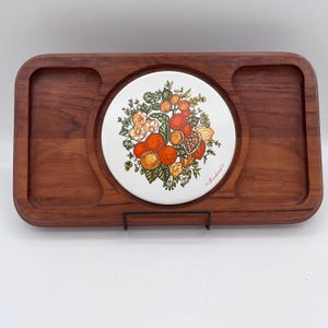 May include: A rectangular wooden serving tray with rounded corners and two recessed side compartments. A circular white ceramic tile is centered in the tray, featuring a colorful illustration of oranges, nuts, and foliage with the text Goodwood.