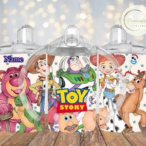 May include: Clear baby bottles decorated with Toy Story characters. The bottles have a clear teat and a wraparound design featuring Woody, Buzz Lightyear, Jessie, and other characters. The word "Name" is visible.