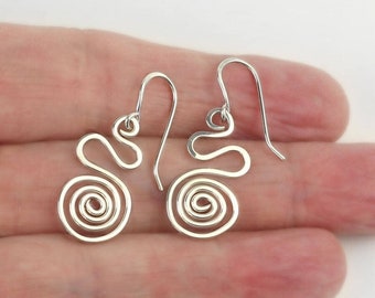 May include: A pair of silver-colored spiral earrings. Each earring features a coiled spiral design with a curved top and a hook for the ear. The earrings are displayed against a neutral background.
