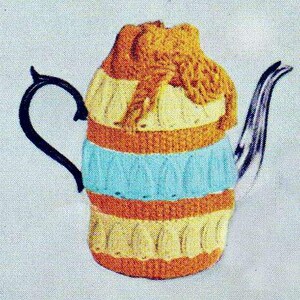 May include: A colorful teapot cozy in shades of yellow, orange, and blue. The cozy is knitted with a textured pattern and covers the teapot. The handle is black and the spout is silver.