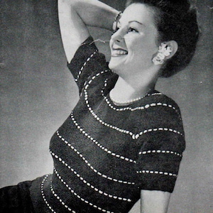 Puede incluir: Top negro de manga corta con líneas de puntos blancos horizontales. El top tiene un cuello redondo y lo lleva una persona con expresión sonriente. La imagen es en blanco y negro.