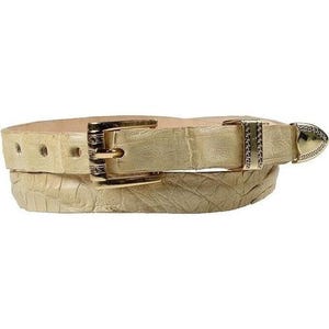 Może przedstawiać: Jasny beżowy pasek z teksturowanym wzorem przypominającym skórę krokodyla. Pasek posiada złotą klamrę i mniejszą, ozdobną klamrę z dżetami. Pasek ma szerokość około 2,5 cm.