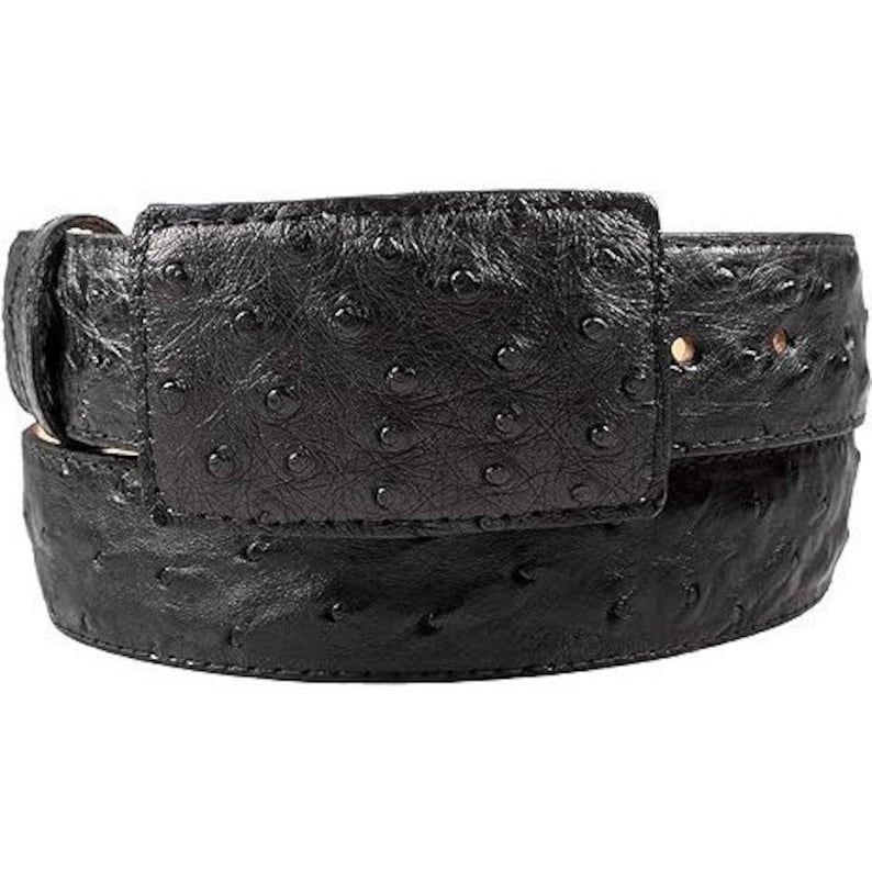 Puede incluir: Un cintur&oacute;n de cuero de avestruz negro con una hebilla grande y rectangular. La hebilla tambi&eacute;n est&aacute; hecha de cuero de avestruz y tiene una superficie lisa y texturizada.