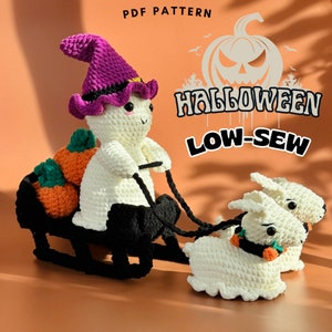 May include: A crocheted ghost wearing a purple hat and holding a string attached to two other crocheted ghosts. The ghosts are pulling a black sled with orange pumpkins on it. The image has the text "Halloween Low-Sew" on it.