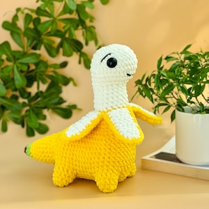 May include: A crocheted banana-shaped plush toy with a white head and yellow body. The toy has black eyes and a small smile.