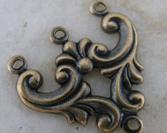 May include: A gold-toned metal connector with a decorative, ornate design. It has four loops for attaching to other jewelry or crafts.