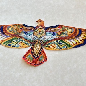 May include: A colorful, detailed illustration of an eagle with outstretched wings. The artwork features intricate patterns in shades of orange, yellow, blue, and purple. The eagle's wings are spread wide, showcasing the elaborate design. The background is a plain, off-white color.