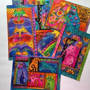 May include: A collection of colorful art prints featuring stylized cats and dogs in vibrant hues of pink, blue, orange, and green. The illustrations include intricate patterns, floral motifs, and the text Kindred Spirits Kindred Souls.
