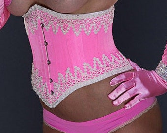 May include: A woman wearing a pink corset with white lace trim and a pink satin bow. She is also wearing pink satin gloves and a pink flower in her hair.