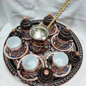 May include: A traditional Turkish coffee set featuring a copper tray, six cups, and a coffee pot. The set is decorated with intricate floral patterns in shades of blue, red, and green.