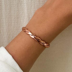 Puede incluir: Una pulsera de cobre trenzada con un acabado en oro rosa.