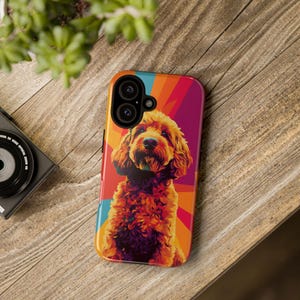 May include: A phone case with a colorful abstract design featuring a brown and white dog. The dog is in the center of the design and is looking at the camera. The case has a cutout for the camera lens.