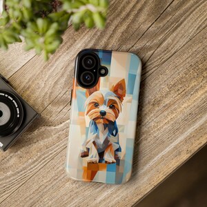Puede incluir: Una funda para teléfono con un diseño geométrico que presenta un perro Yorkshire Terrier con pelaje marrón y tostado. La funda tiene una combinación de colores azul, blanco y naranja.