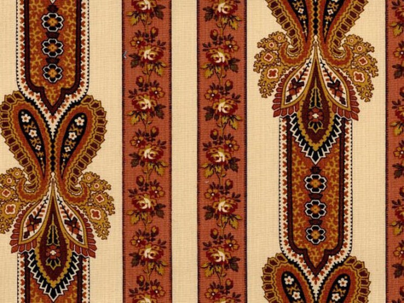 May include: A fabric with a repeating pattern of paisley designs in shades of brown, orange, and black on a cream background.