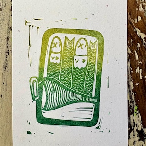 May include: A rectangular print on textured white paper featuring a green gradient linocut illustration of an open tin of sardines. The design shows three fish with heart-shaped markings and a textured lid pulled back to reveal the contents inside.