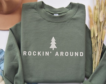 May include: A green sweatshirt with a white embroidered pine tree and the text "Rockin' Around".