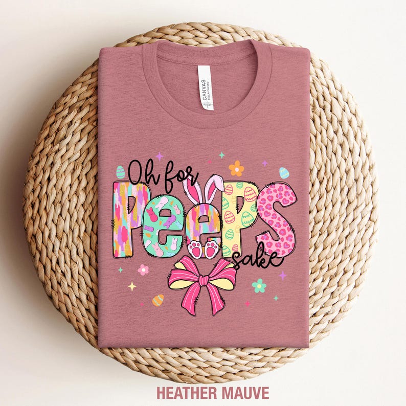May include: A heather mauve t-shirt with the text "Oh for Peeps sake" in colorful letters with a bunny and Easter egg designs.