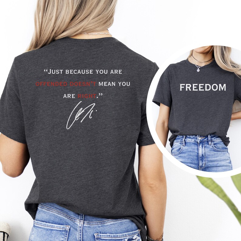 May include: Dark gray t-shirts with white text. One shirt reads "FREEDOM" in a bold font. The other shirt has the quote "JUST BECAUSE YOU ARE OFFENDED DOESN'T MEAN YOU ARE RIGHT." in white and red.