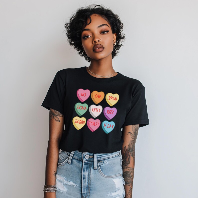 May include: Black t-shirt with a graphic of colorful candy hearts with phrases like "No Cap", "Bruh", "Sigma", "Ohio", "Rizzz", "Skibidi", "Toilet", and "V Day".