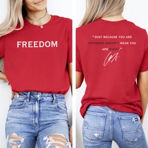 May include: Red t-shirt with the word "FREEDOM" printed in white on the front. The back of the shirt features the quote, "JUST BECAUSE YOU ARE OFFENDED DOESN'T MEAN YOU ARE RIGHT." in white, along with a signature.