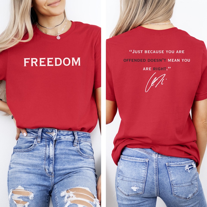 May include: Red t-shirt with the word "FREEDOM" printed in white on the front. The back of the shirt features the quote, "JUST BECAUSE YOU ARE OFFENDED DOESN'T MEAN YOU ARE RIGHT." in white, along with a signature.
