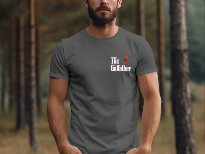 May include: A dark grey t-shirt with a white graphic that says "The Golfather" with a red golfer silhouette.