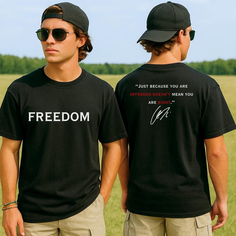 May include: Black crew neck t-shirt with the word "FREEDOM" in white block letters on the front. The back of the shirt has the quote "JUST BECAUSE YOU ARE OFFENDED DOESN'T MEAN YOU ARE RIGHT." in white and red, with a signature.