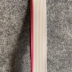 Könnte beinhalten: Ein graues und rotes Flachbandkabel mit zwei schwarzen Steckern. Das Kabel ist etwa 30 cm lang.
