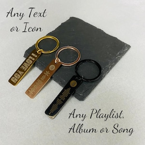 May include: Three metal keyrings in gold, rose gold, and black. The gold keyring has the text "I LOVE YOU". The other two keyrings feature a music waveform design. The text "Any Text or Icon" and "Any Playlist, Album or Song" are also visible.