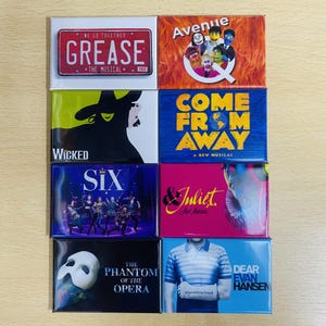 Może przedstawiać: Kolekcja prostokątnych magnes&oacute;w z logo i grafiką z r&oacute;żnych musicali broadwayowskich. Magnesy prezentują tytuły takie jak "Grease", "Wicked", "Six", "The Phantom of the Opera", "Avenue Q", "Come From Away" i "& Juliet", w żywych kolorach.